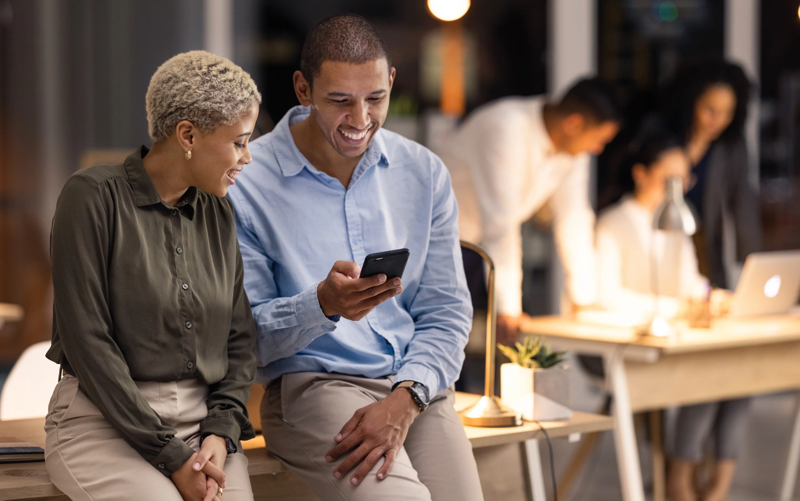 Zwei Menschen schauen lachend auf ein Handy